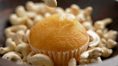Fresh baked muffin with falling raw cashew nuts around