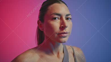 Portrait tired sportswoman breathing hard at neon gym. Woman looking camera
