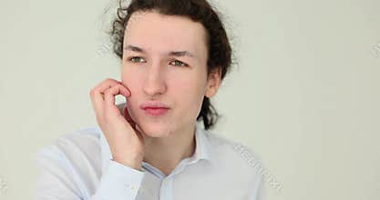 Young man scratching cheek with a frowning expression on his face on a white background