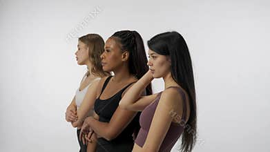 Portrait of young multiethnic models on white studio background close up. Group of three appealing multiracial girls