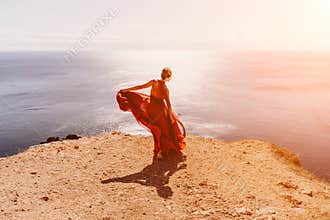 Woman red dress sea. Female dancer in a long red dress posing on a beach with rocks on sunny day. Girl on the nature on