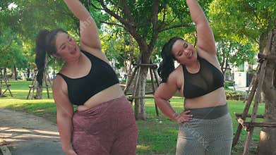 Obese two young asian woman doing stretching arm muscle in the park.