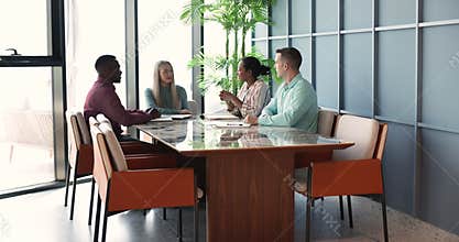 Four businesspeople talking gathered in modern meeting room