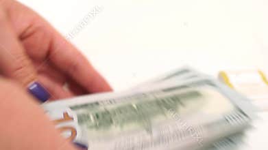 Female hands, dollar counting. Depicting finance and accounting themes. A person is counting 100 dollar bills on a white
