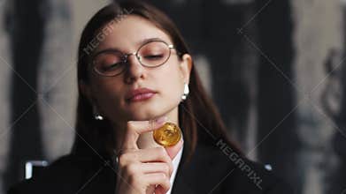 Thoughtful woman showing bitcoin, thinking female with golden coin and looking at camera. cryptocurrency concept