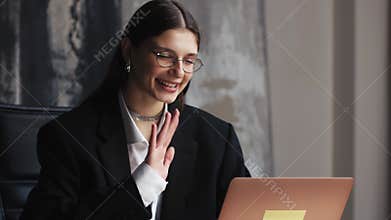 A woman in formal wear and eyewear smiling at an online event. communicating by video call. businesswoman speaking
