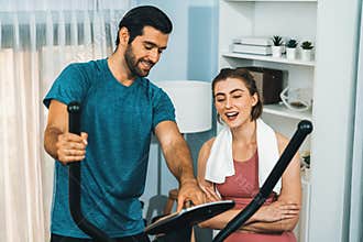 Athletic and sporty couple running on elliptical running machine at gaiety home.