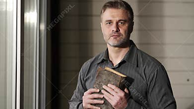 Pastor reads bible in preparation for sermon. Adult man is holding the bible in his hands. He is looking at the camera