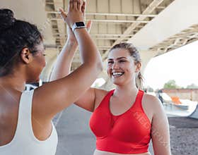 Smiling plus-size woman giving five to her fitness buddy