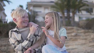a boy and a girl are sitting next to each other on the beach