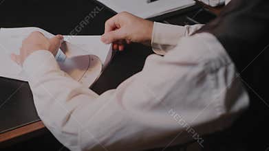 A businessman is concentrating on analyzing charts and graphs at his office desk