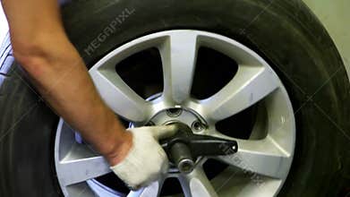Car wheels spins on balance adjustment stand, man