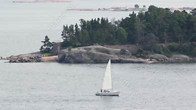Yacht sail beside rocky coast with beacon and