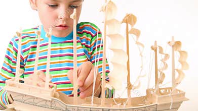 boy with interest constructing toy model of ship