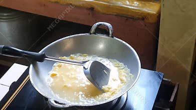 Pouring water into mixed egg or beaten egg or whisked egg in the frying pan on the lit black stove.