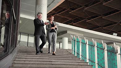 Two senior business man and woman in formal meeting and discussing documents and using a tablet.