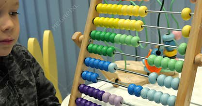 Boy elementary school student moves wooden beads on abacus