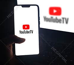 Man watching movies and series on YouTube TV service through smartphone, editorial background