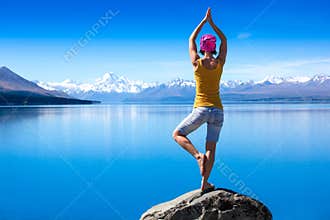 An attractive young woman doing a yoga pose for balance and stretching near the lake