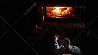 A man drinks brandy by the fireplace. Top view