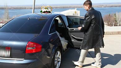 bridegroom opens door of car and offers one\'s hand