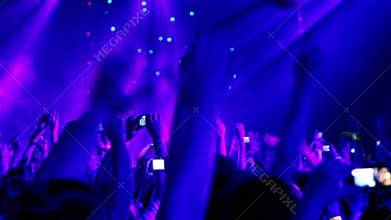 Many people at rave party, view from behind, hands