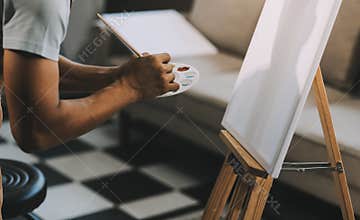 Young male artist painting picture in studio