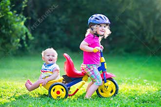 Two kids on a bike in the garden