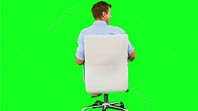 Smiling man turning on swivel chair on green screen