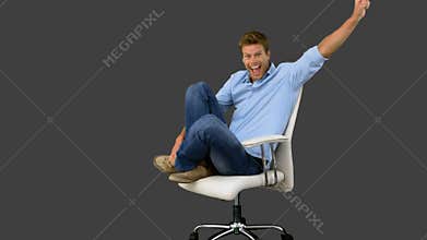 Smiling man cheering and turning on swivel chair on grey screen
