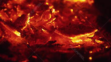 Hot coals with ash flying onto them.