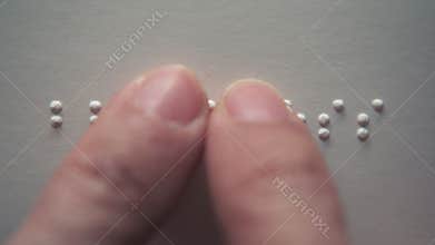 Visually impaired people reading a Braille word \"blindness\" on paper with their fingers
