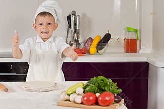 Excited little boy cooking pizza doing a thumbs up