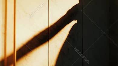 Hand shadow reaching on a sunny marble wall