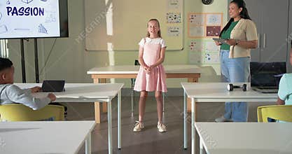 Teacher with tablet watching teenage girl speaking, gesturing in class as PASSION display inspiring