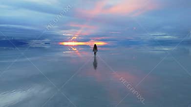 A solitary figure walks across the expansive Salar de Uyuni in Bolivia, capturing the surreal beauty of the world's largest