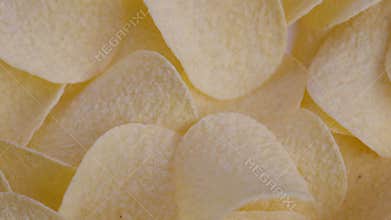 Closeup potato chips stacked golden crisp texture, overlapping thin curved crisps, light salt dusting, inviting crunchy snack shot