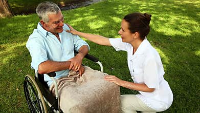 Nurse talking to man in wheelchair outside