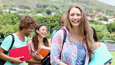 Pretty student smiling at camera with classmates behind