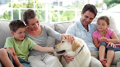 Cute family relaxing together on the couch with their labrador dog