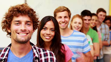 Students standing in classroom giving thumbs to camera in a line