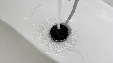 Close-up of running water hitting drain stopper in a