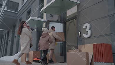 Woman walks with toddler while man carries cardboard boxes