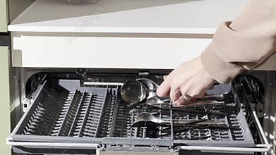 Person removes clean spoons from the top cutlery tray of