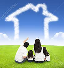 Happy family sitting on a meadow with house of clouds
