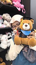 Happy Hijab Woman Holding Graduation Teddy Bear In Shop