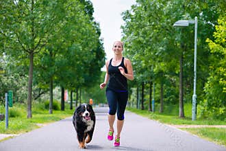 Sports outdoor - young woman running with dog in park