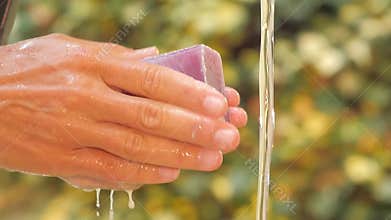Close up of woman's hands and soap under pouring water