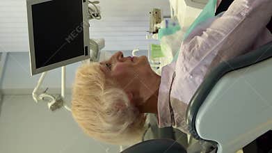 Friendly dentist warmly greets senior female client in his modern office