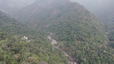 Epic aerial view of the vast, jungle-covered mountains and a deep river valley in the hazy landscape of Cherrapunji, Meghalaya,